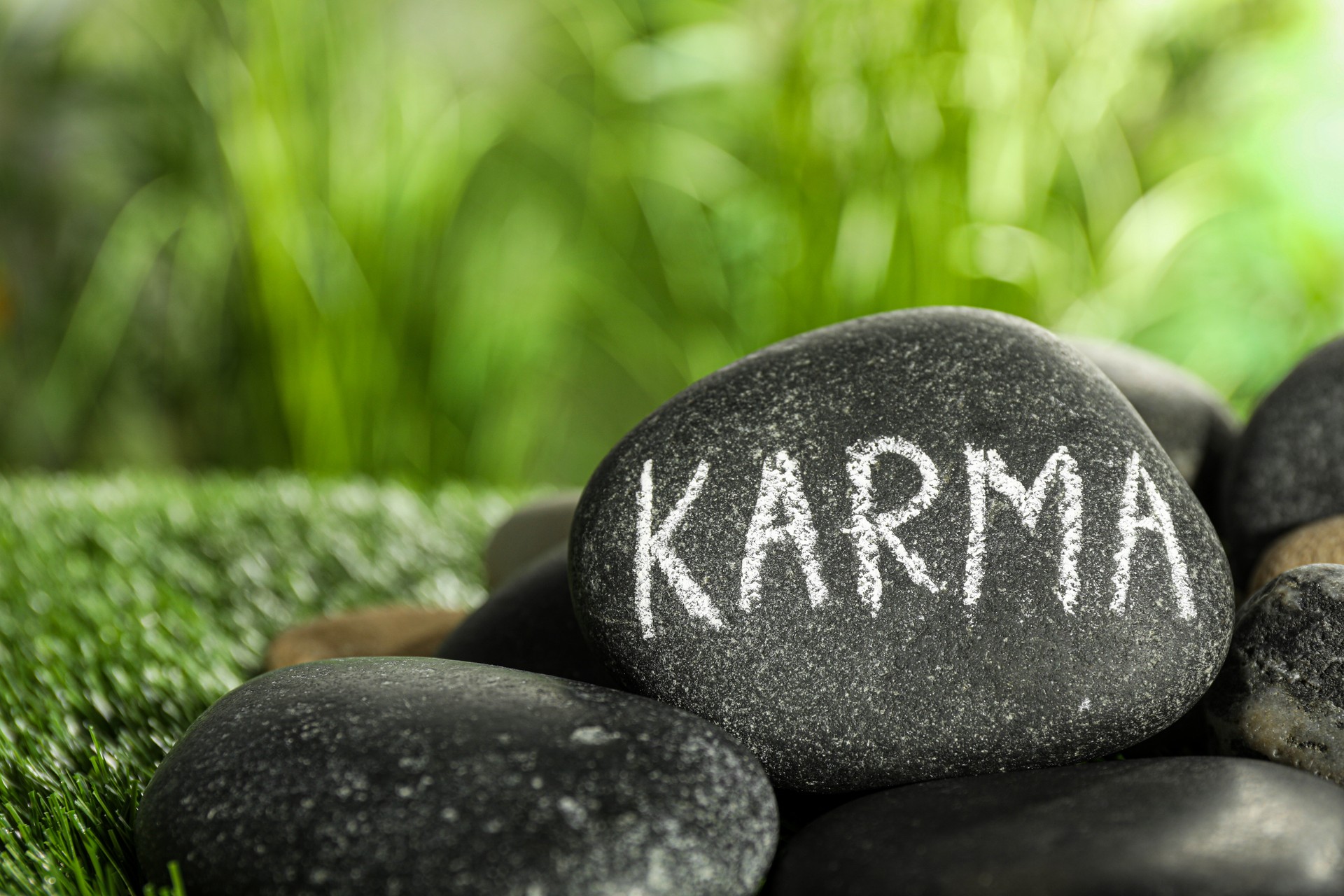 Stones with word Karma on green grass, closeup. Space for text